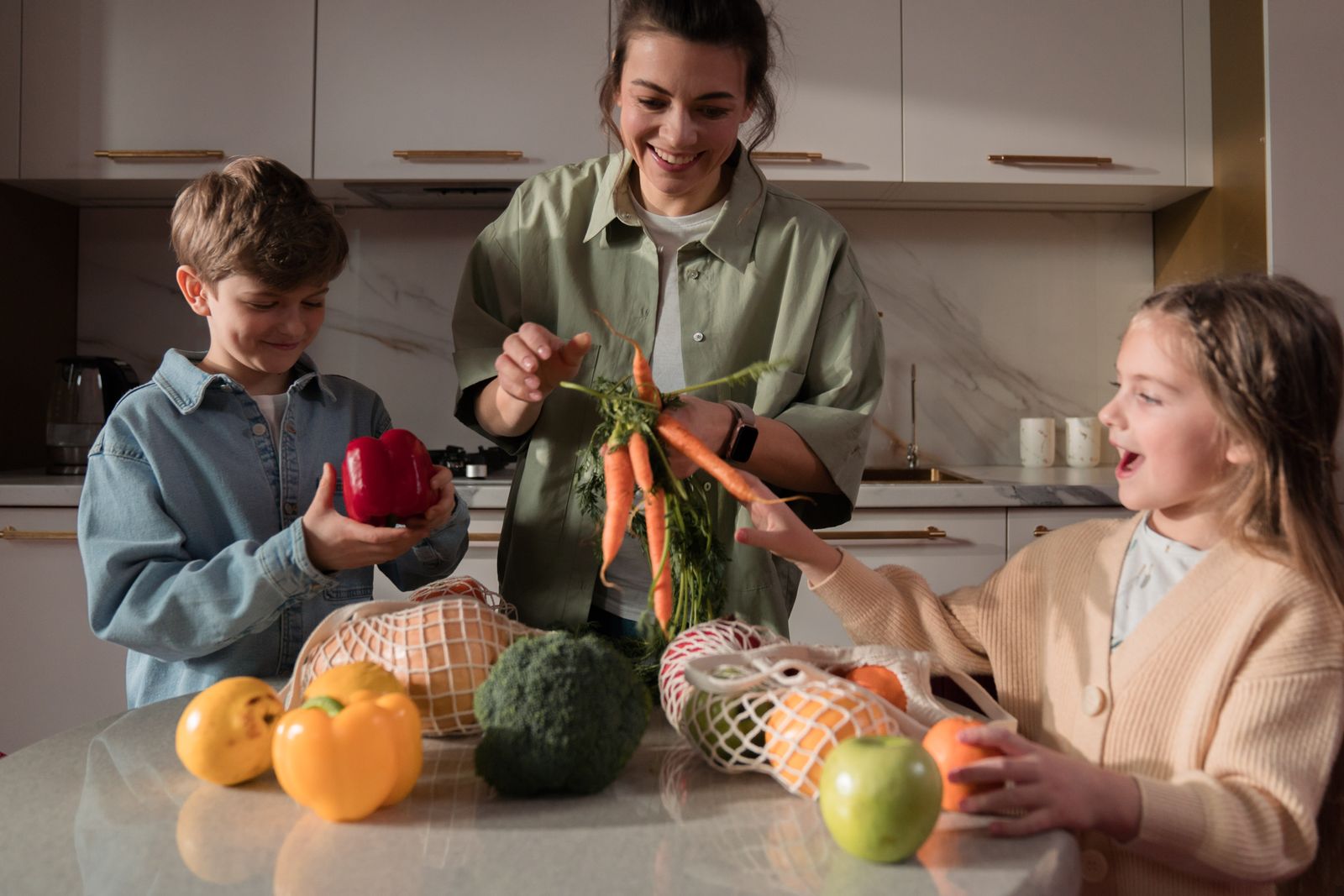 Une mère et ses deux enfants déballent les courses dans la cuisine.